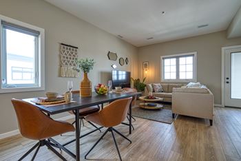 A dining room with a table set for two and a couch.